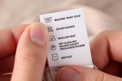 Woman holding a dress label with washing instructions and symbols