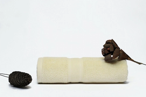 Pearl white towel photographed on a white background with black pinecones flowers..