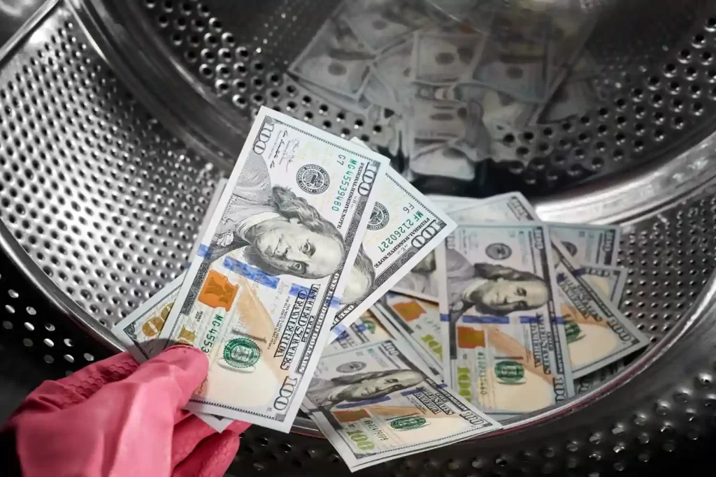 closeup person hand rubber glove putting dollars in washing machine